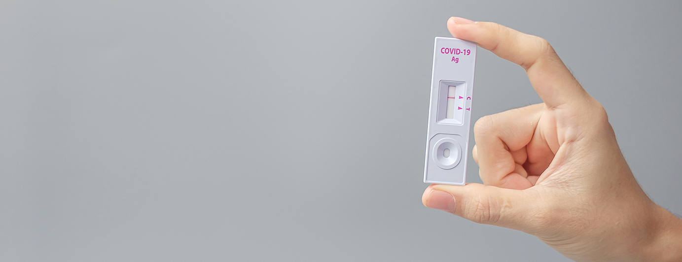 A photo of a hand holding a COVID-19 rapid antigen test device. The test shows only one red line which means it is a negative result.